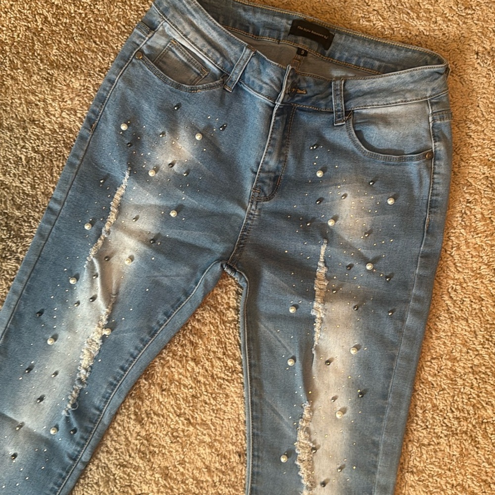 Distressed jeans with a pearl and sparkle decor. Fringe hem bottom